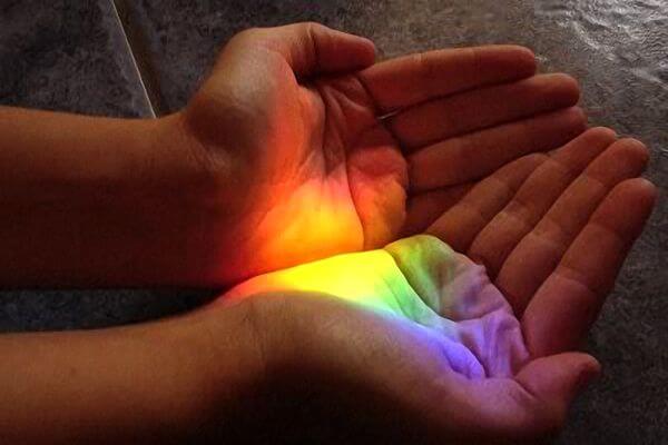 Two hands cupped gathering a rainbow of light